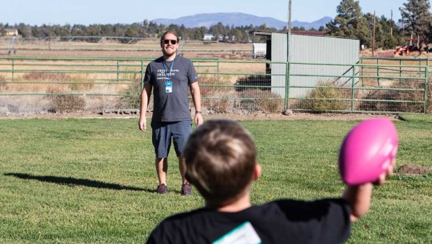 Friends of the Children Central Oregon mentor Aaron Hinkley plays catch with one of the kids he mentors through the program while at the organization’s ranch outside Bend in 2023.  