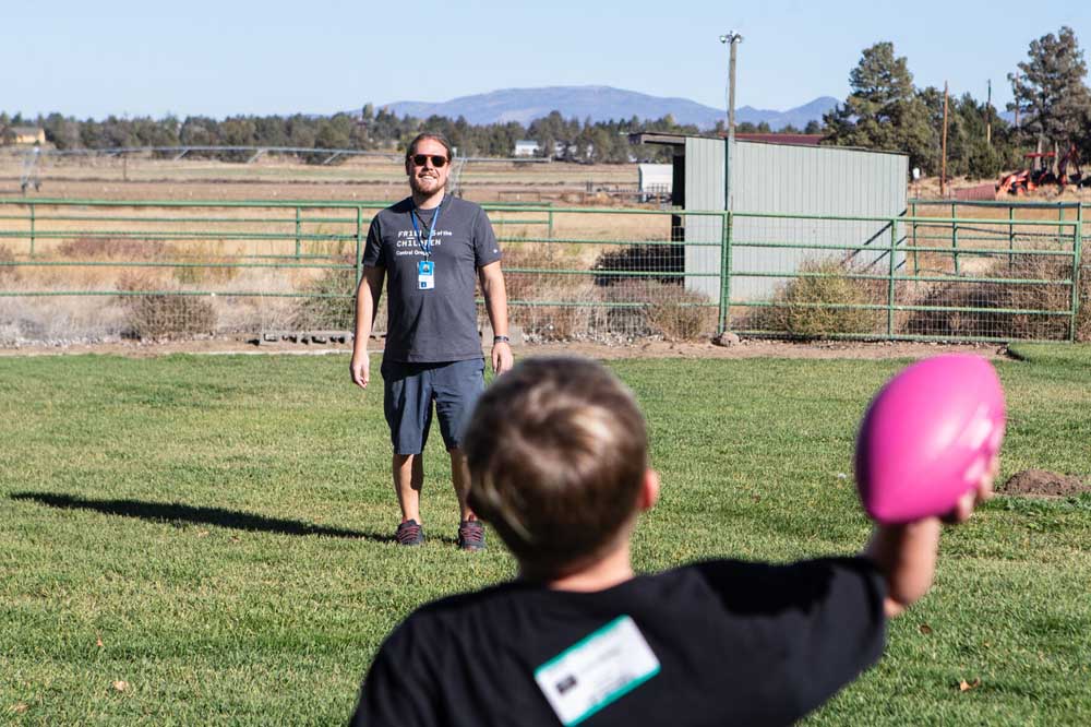 Friends of the Children Central Oregon mentor Aaron Hinkley plays catch with one of the kids he mentors through the program while at the organization’s ranch outside Bend in 2023.  
